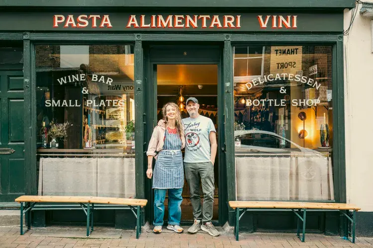 Harry and Simona standing in the doorway of Cantina Caruso, under the Pasta Alimentari Vini sign